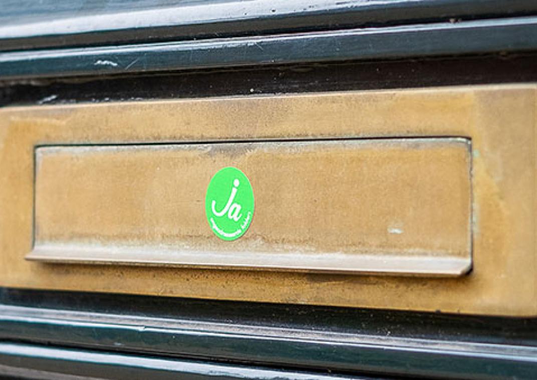 De groene ronde Ja sticker op de klep van een brievenbus geplakt