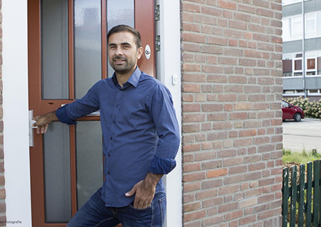 Een pan staat in zijn deuropening met zijn hand op de deurklink terwijl hij ons aankijkt