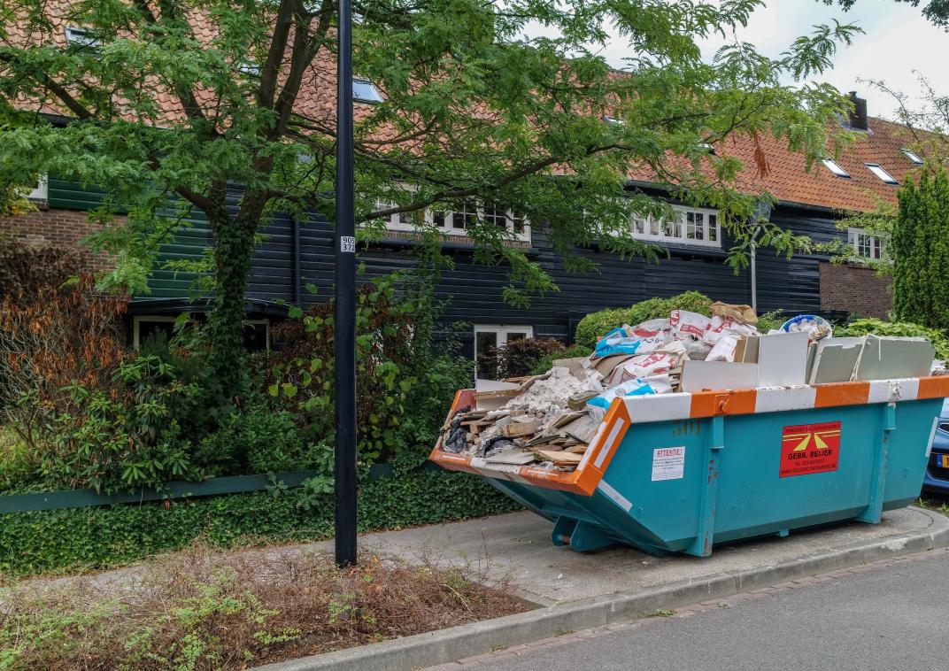 Volle bouwcontainer aan de weg