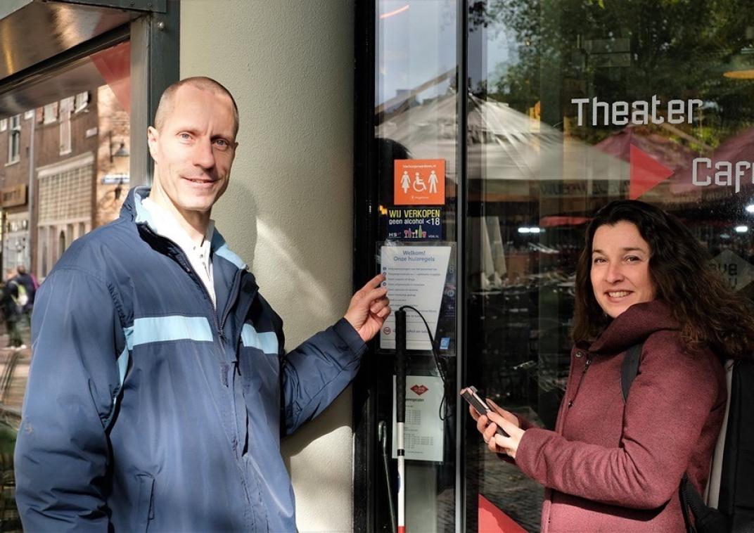 2 personen staan bij een deur met een pamflet