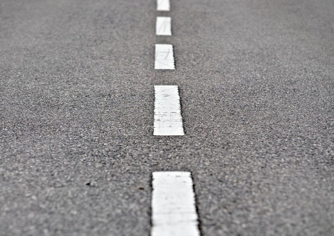 Grijs wegdek met witte onderbroken middenstreep