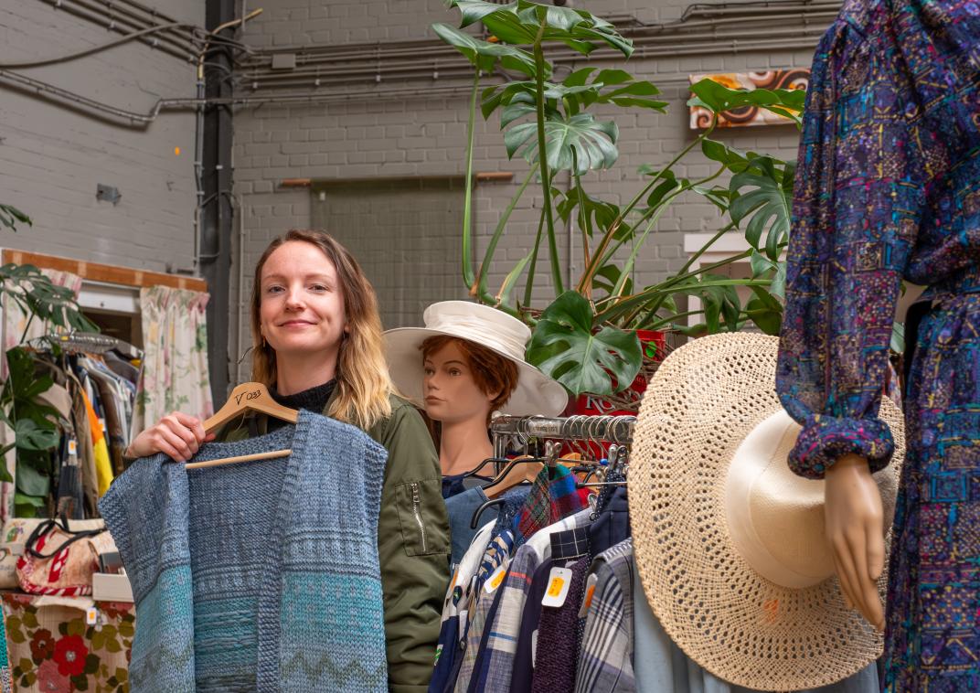 Een vrouw koopt kleding in een kringloopwinkel.