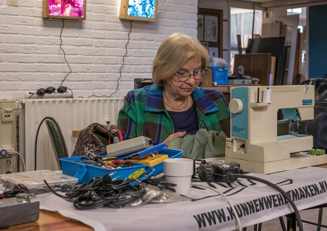 Vrouw achter een naaimachine om kleding te repareren