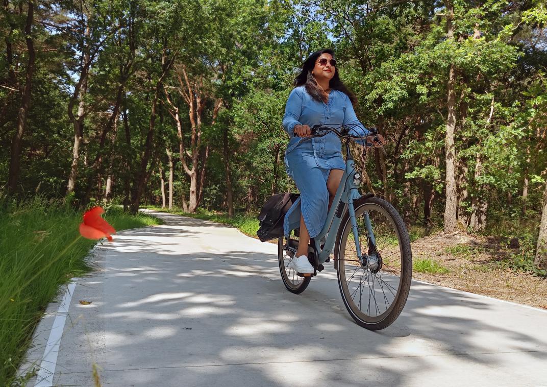 Vrouw op fiets op een fietspad in de bossen