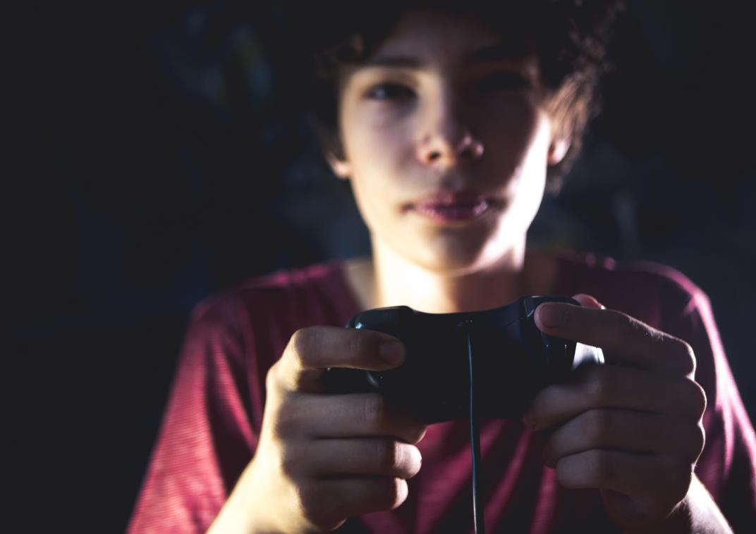 Een jongen zit met een gameconsole in zijn handen.