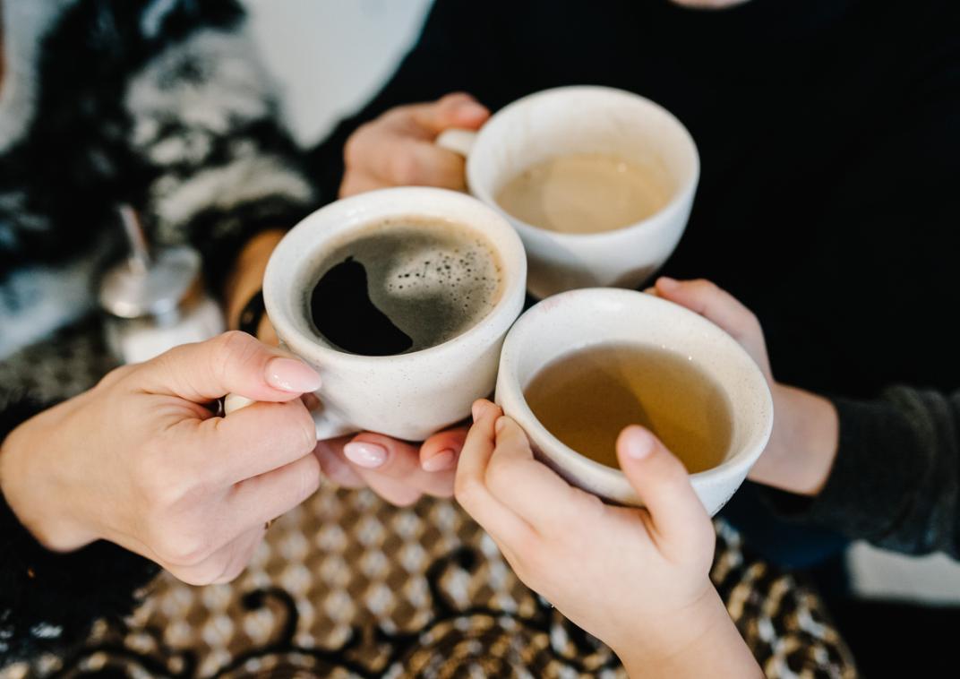 Drie mensen in een kring met drie koppen koffie in hun handen.