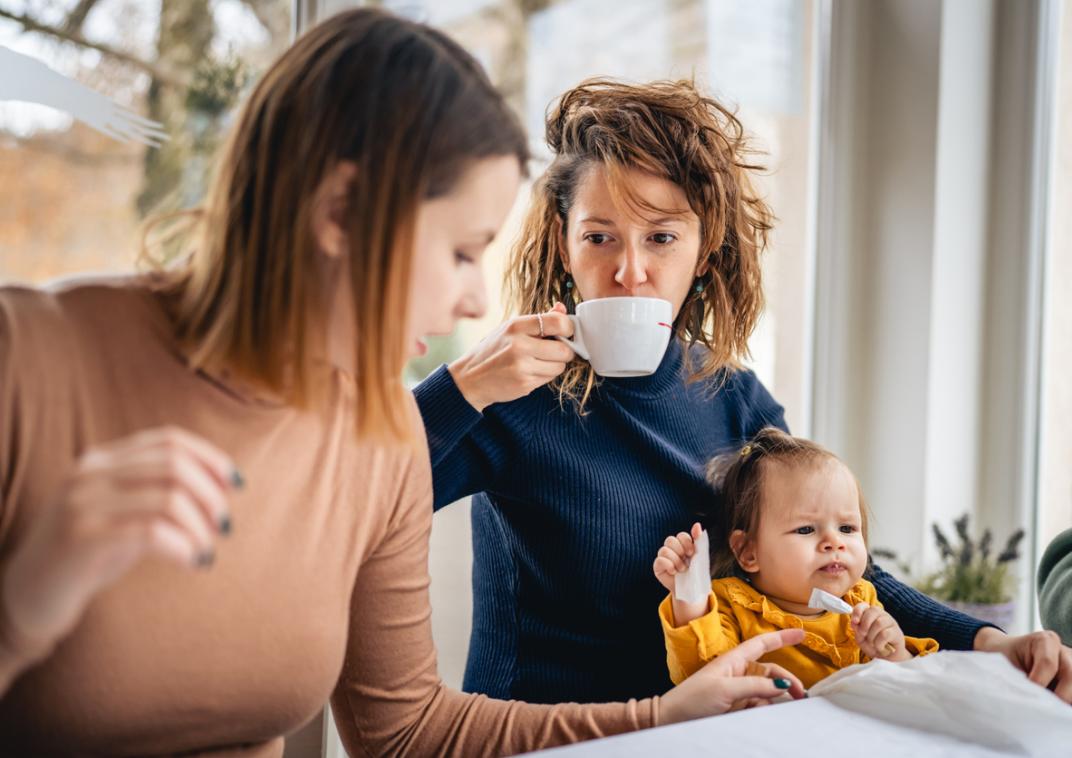 Twee vrouwen in gesprek met koffie en een kind op schoot