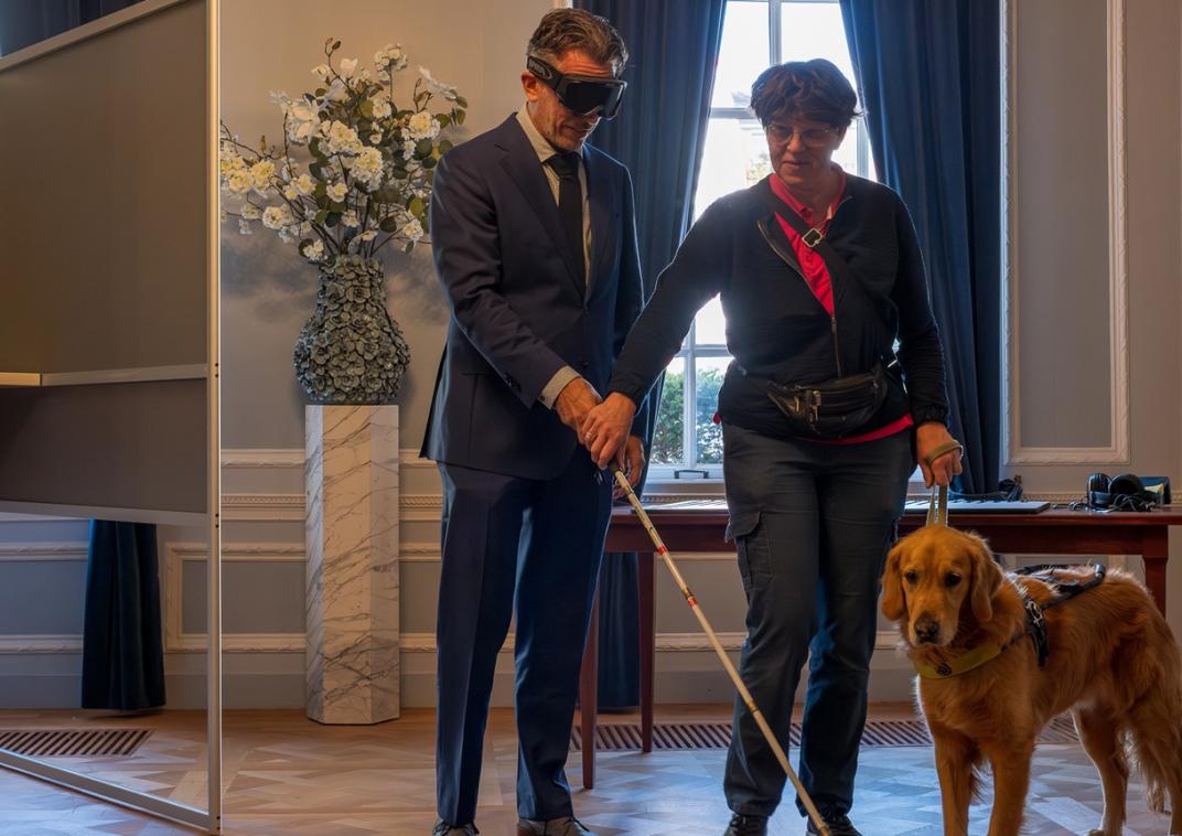 Minister Rijkaart stemt in een toegankelijk stembureau met een geblindeerde skibril