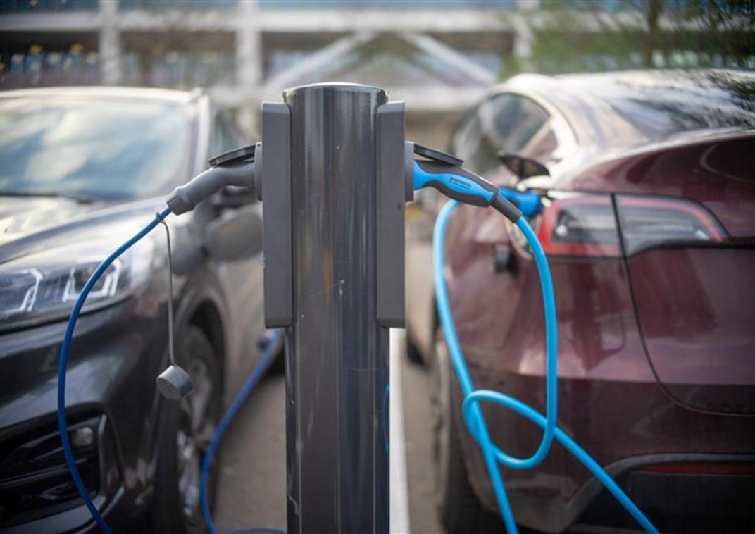 Een laadpaal voor elektrische auto's met daaraan 2 auto's die opladen