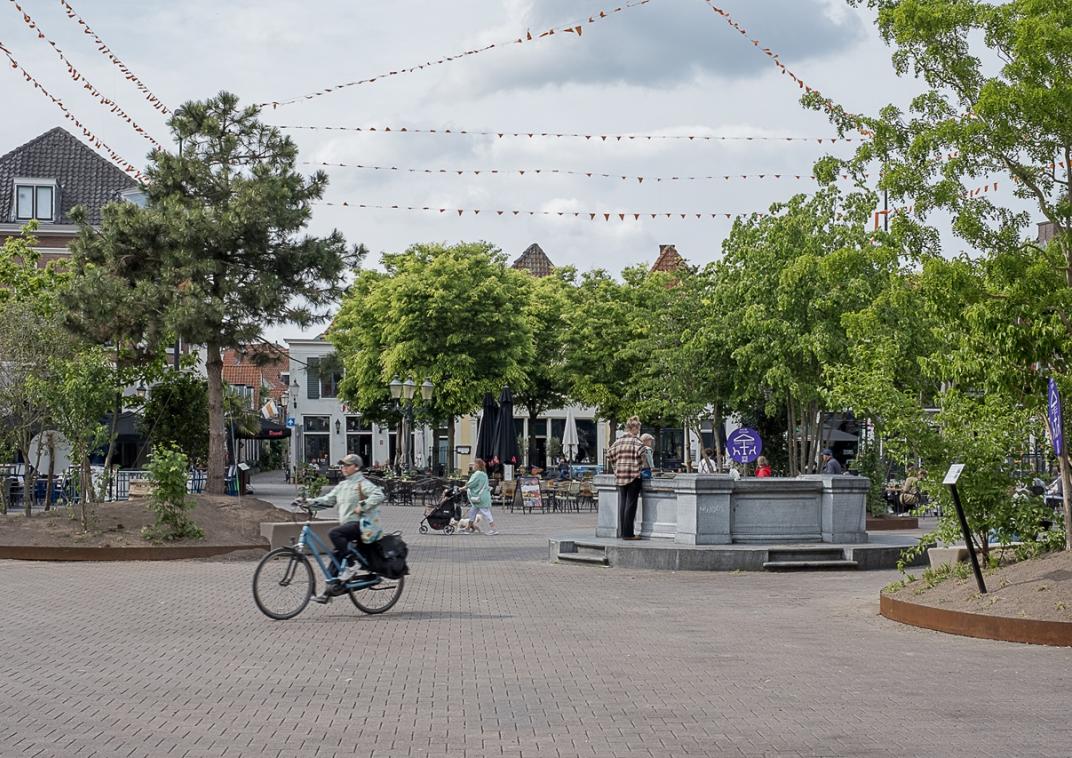 Overzicht van de verplaatsbare bloembakken op plein Hof als proef. Met een fietser op de voorgrond 
