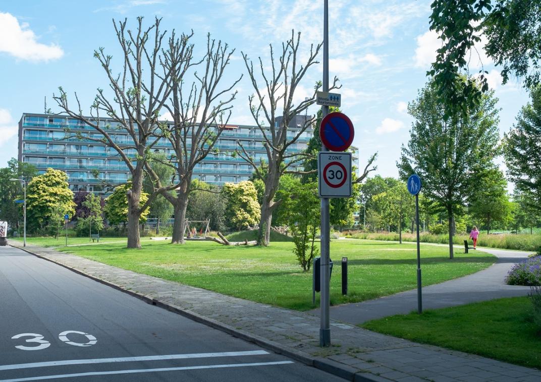 Een lege straat met op de weg een tekst met de snelheidslimiet van 30 km per uur