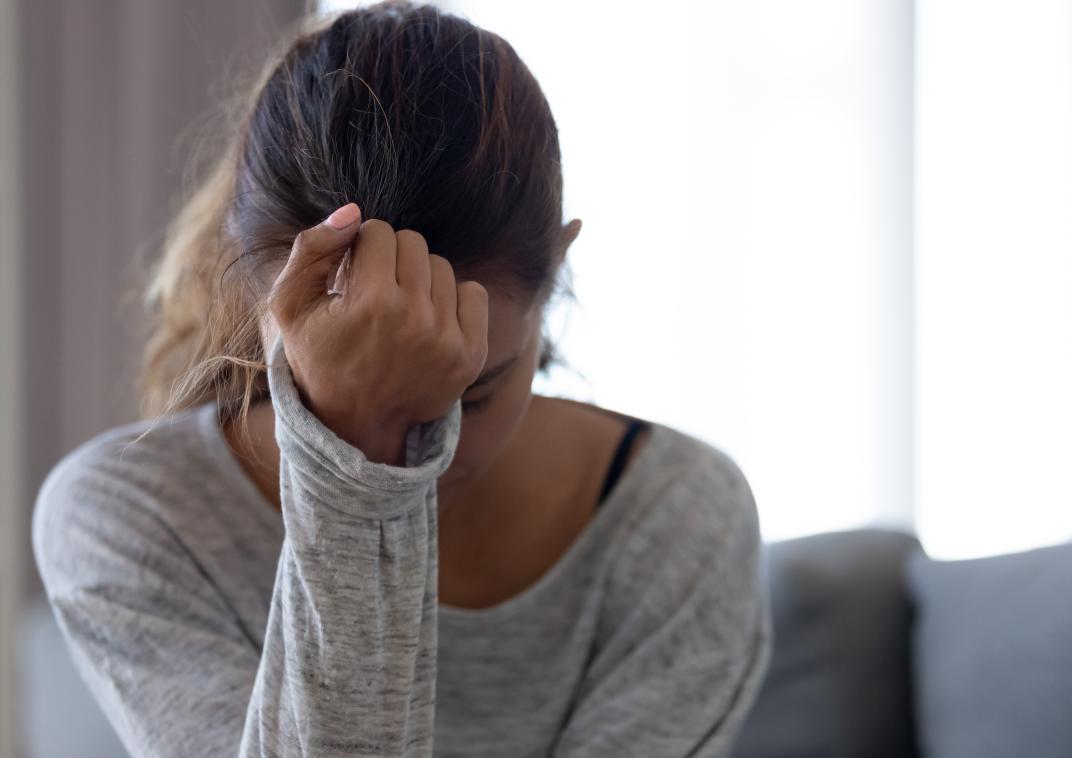 vrouw leunt met hand op voorhoofd
