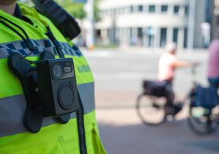 Een handhaver die een Bodycam draagt met op de achtergrond twee fietsers