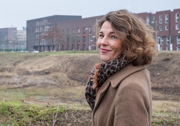 Glimlachende vrouw bij leeg grondgebied stadhuis en woningen