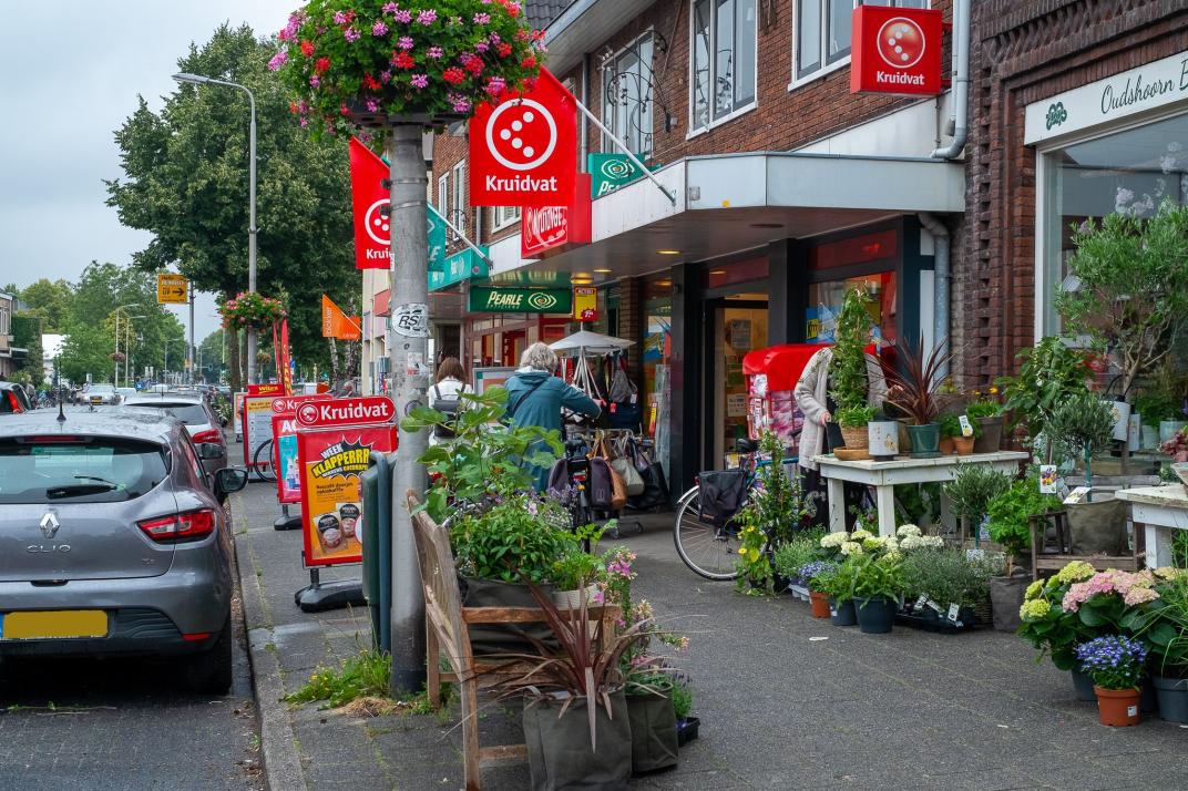 Een Kruidvat filiaal met rode vlaggen en straatborden