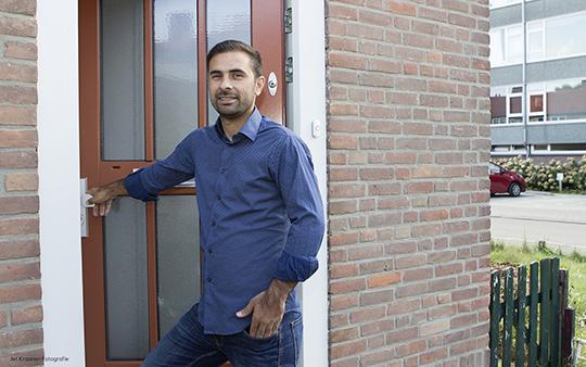 Een pan staat in zijn deuropening met zijn hand op de deurklink terwijl hij ons aankijkt