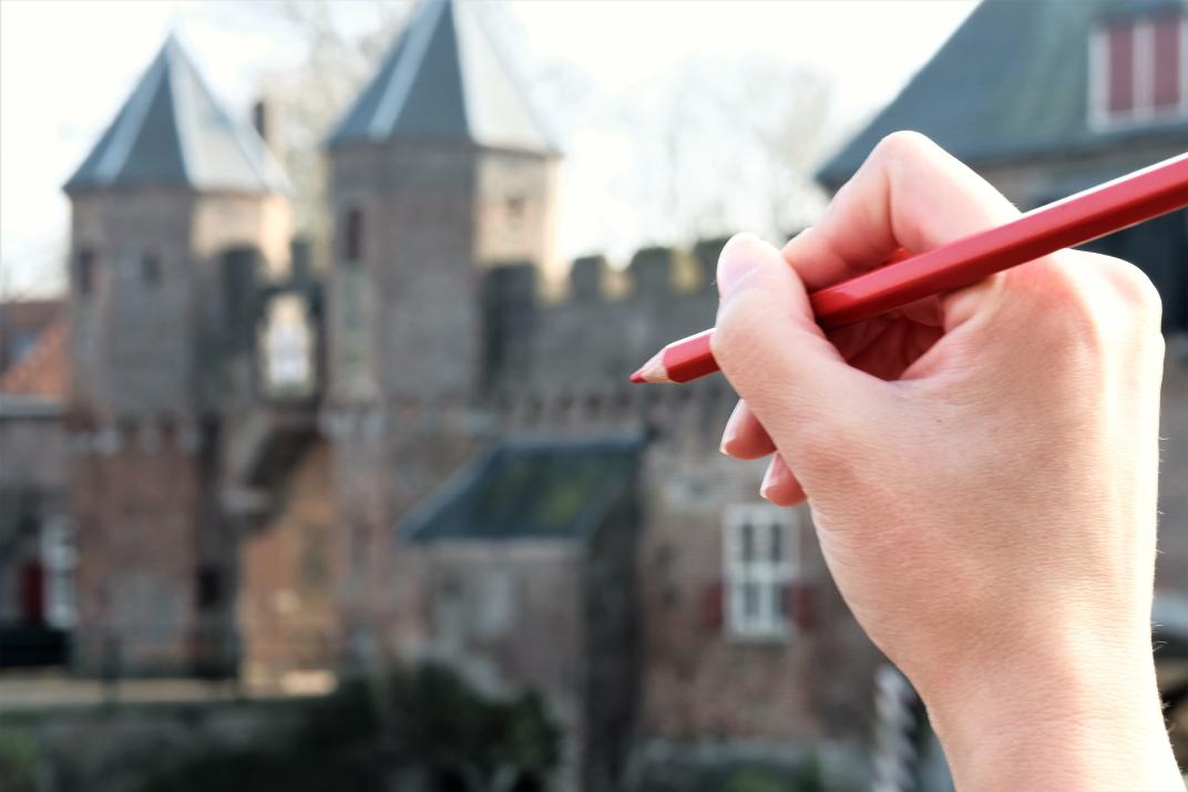 Afbeelding met de Koppelpoort op de achtergrond en een hand met een rood stempotlood op de voorgrond.