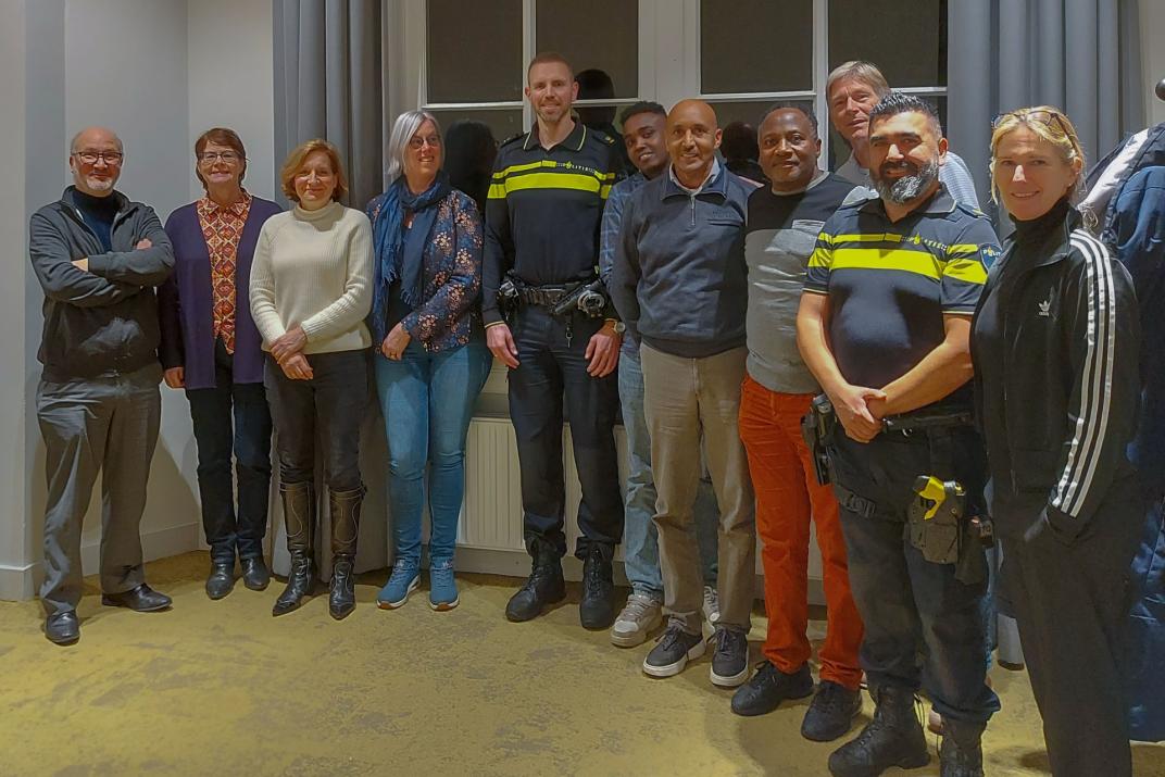 Groepsfoto van meerdere mensen op een rij waaronder ook politieagenten.