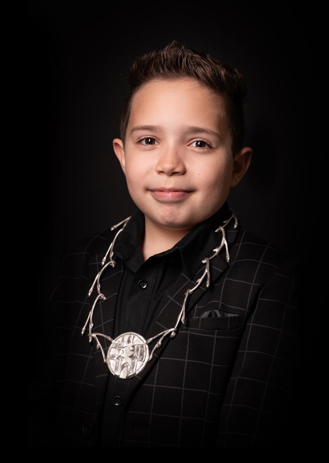Trotse Aiden met zijn ambtsketen om