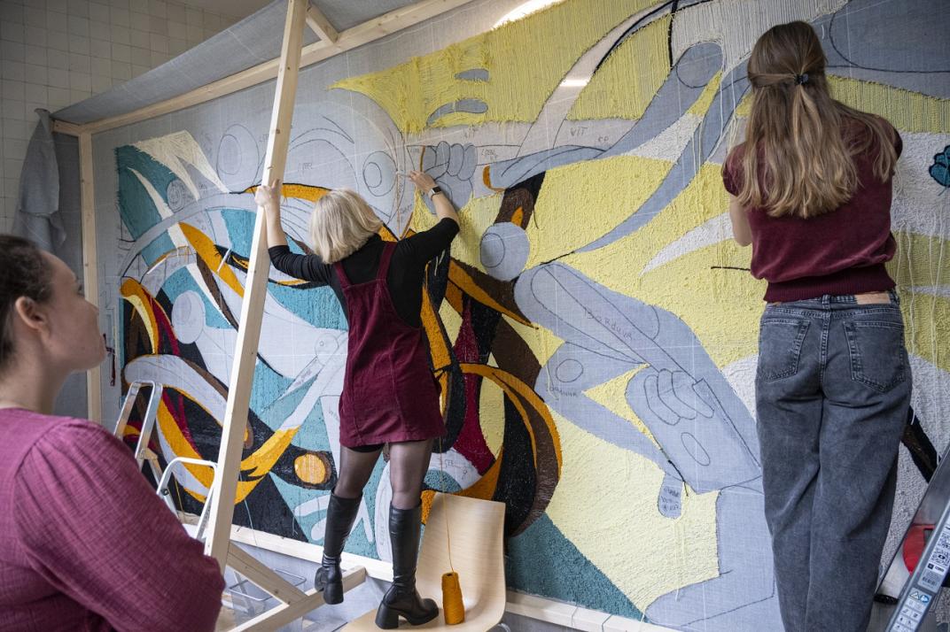 Mensen werken aan een wandkleed over het slavernijverleden