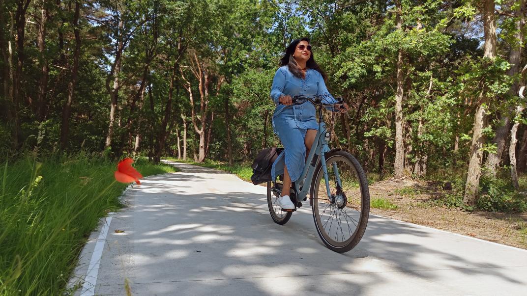 Vrouw op fiets op een fietspad in de bossen