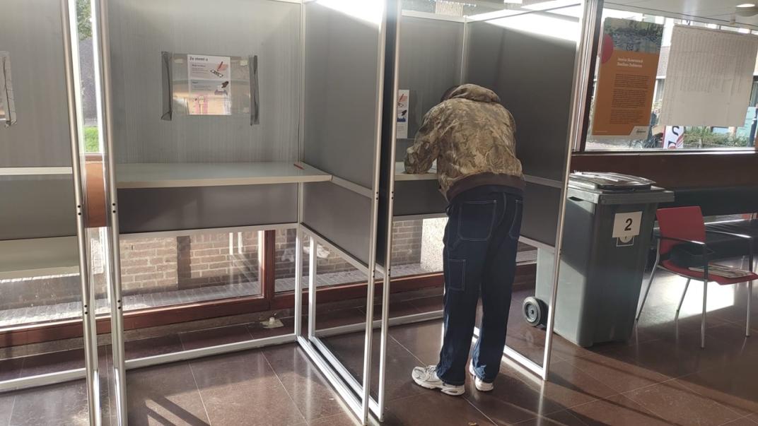 Een persoon in een stemhokje in het gemeentehuis