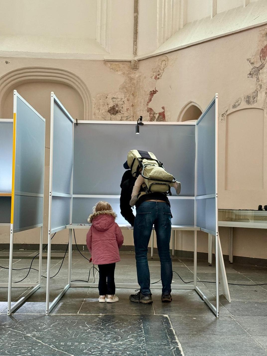 een persoon met kind in een stemhokje