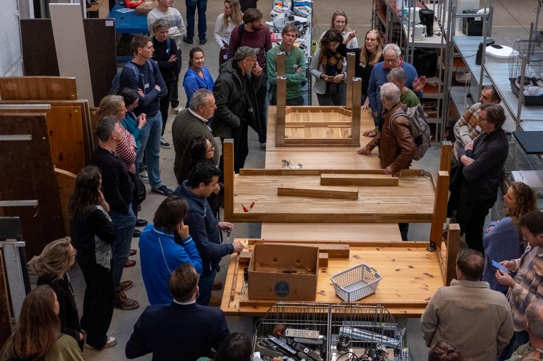 Mensen staan om tafels heen met uitleg over van stort naar start