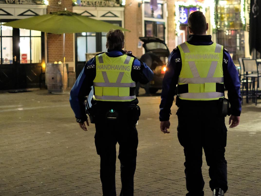 Twee handhavers oprug gezien en horeca op achtergrond